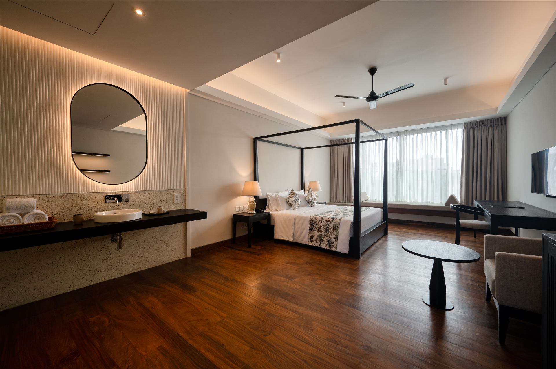 Spacious guest room with lounge chair, vanity and four-poster bed